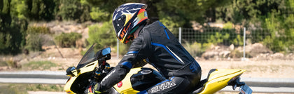 divisible motorcycle suit outfitted by 2 riders while riding bikes on a race track